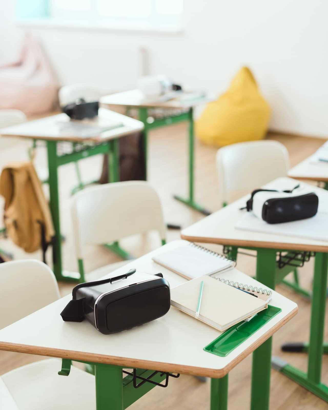 VR headsets resting on school desks beside notebooks in a bright classroom
